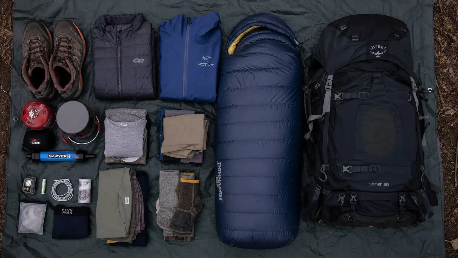 Camping gear laid out flat next to a 50L backpack showing a two-night kit fitting inside