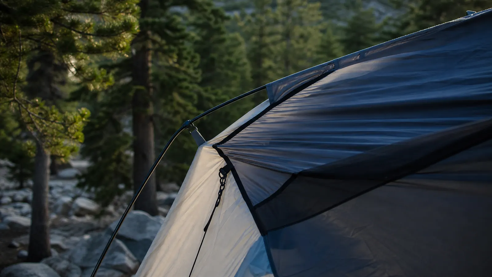 Close-up of a fiberglass tent pole flexing visibly in windy conditions with the tent fabric stressed to one side