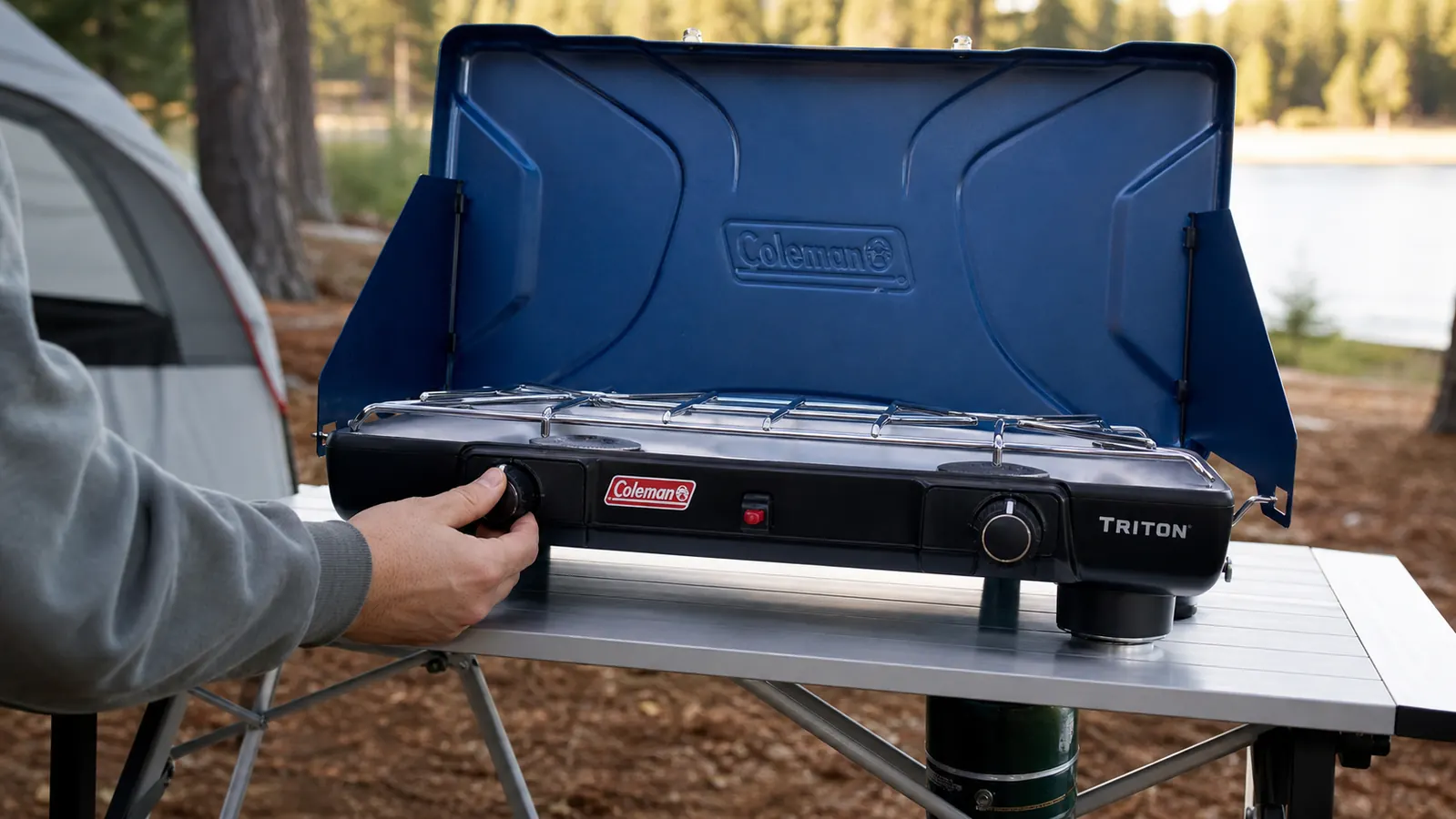 Hands adjusting the burner knob on the Coleman Triton 2-burner propane stove at a campsite