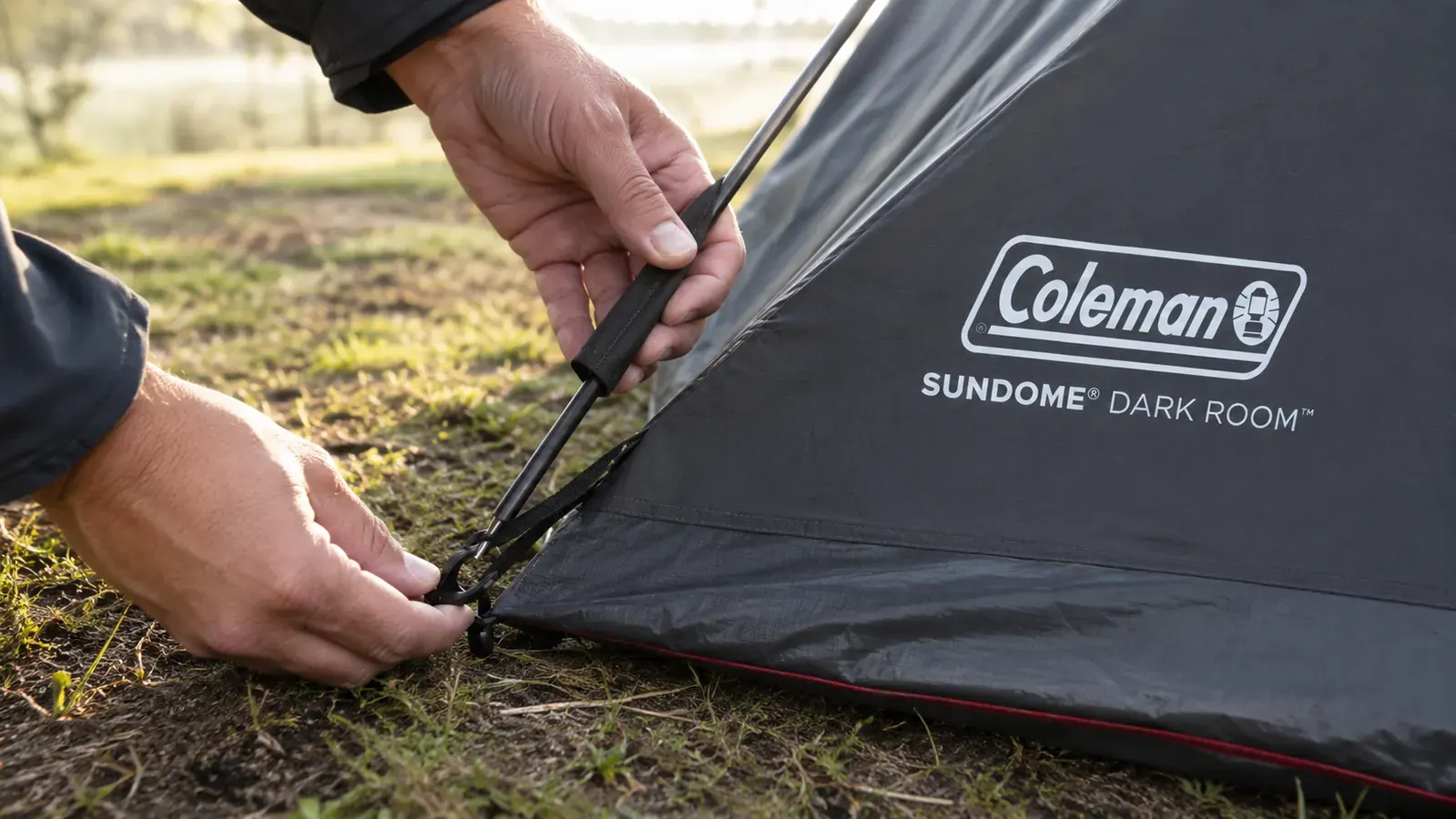 Close-up of tent pole being threaded through sleeve and clipped to corner grommet during solo tent setup