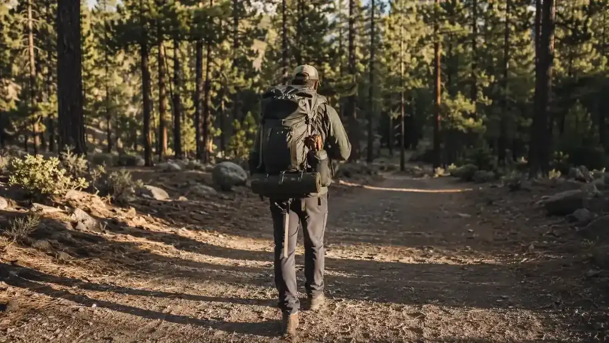 Weekend camper on a forest trail with a fully loaded backpack, headed toward a campsite
