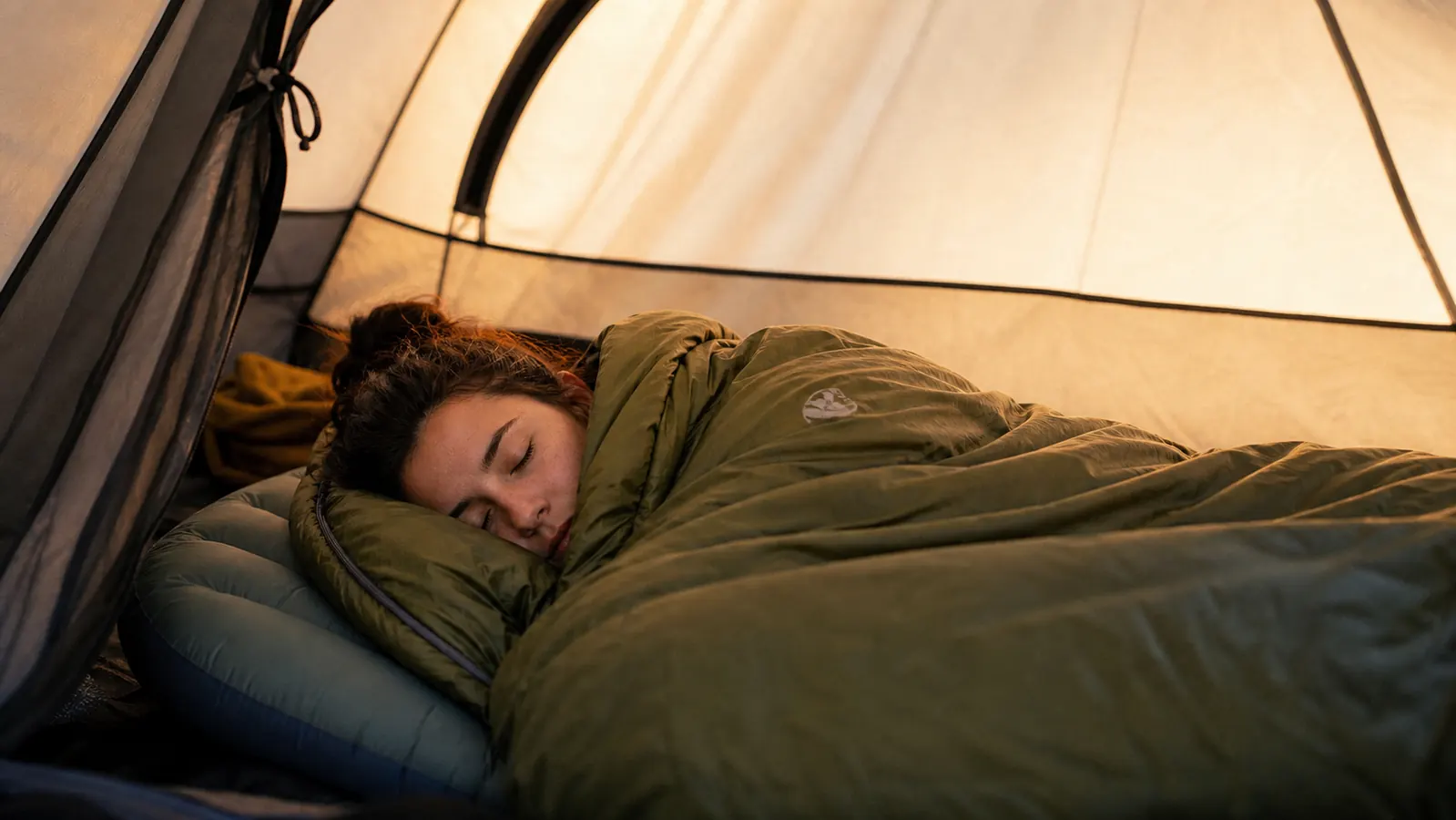 Camper sleeping soundly in a tent, morning light visible through the tent fabric
